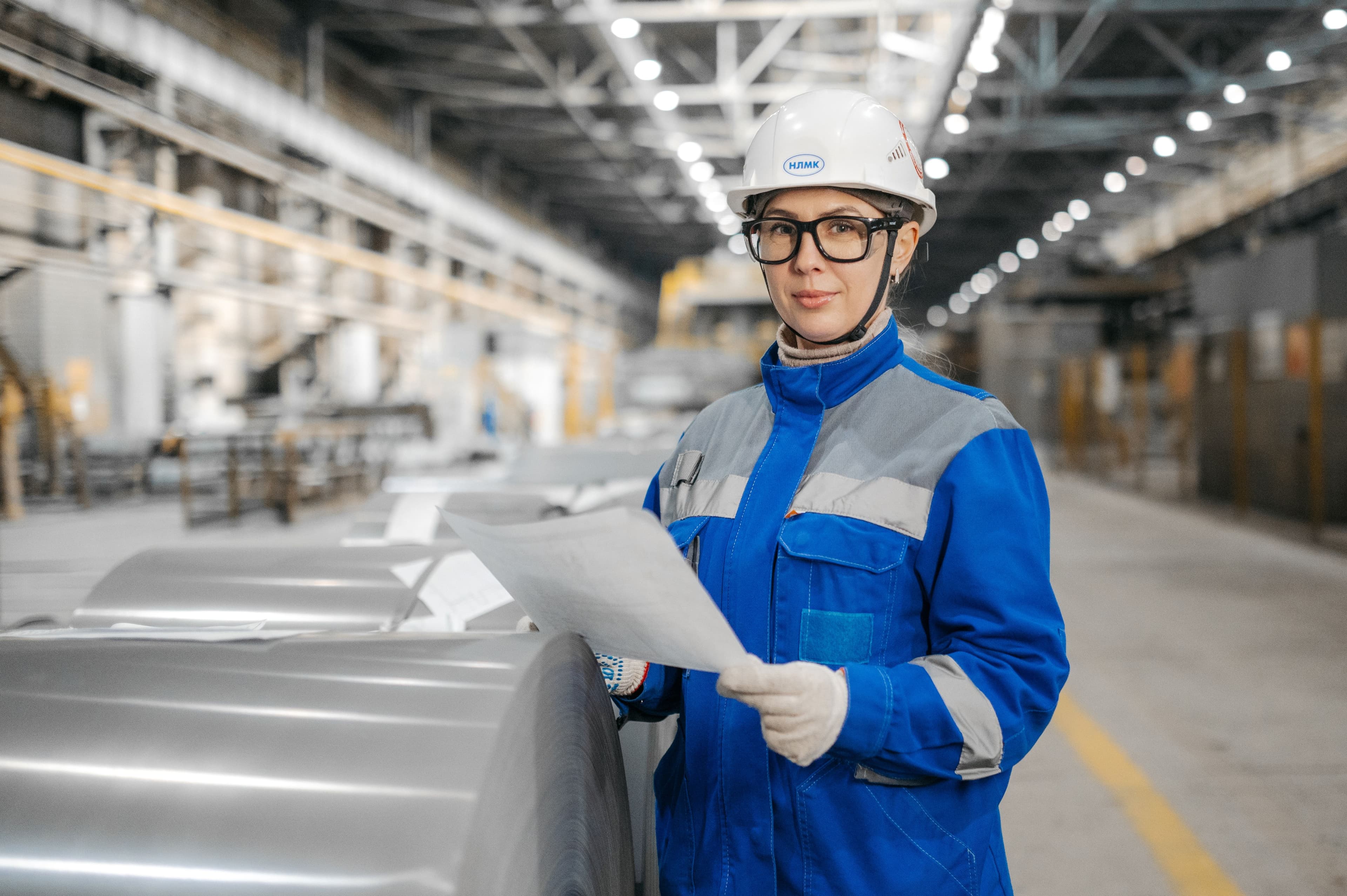 Steel plant engineer reviewing specification documents beside coiled steel