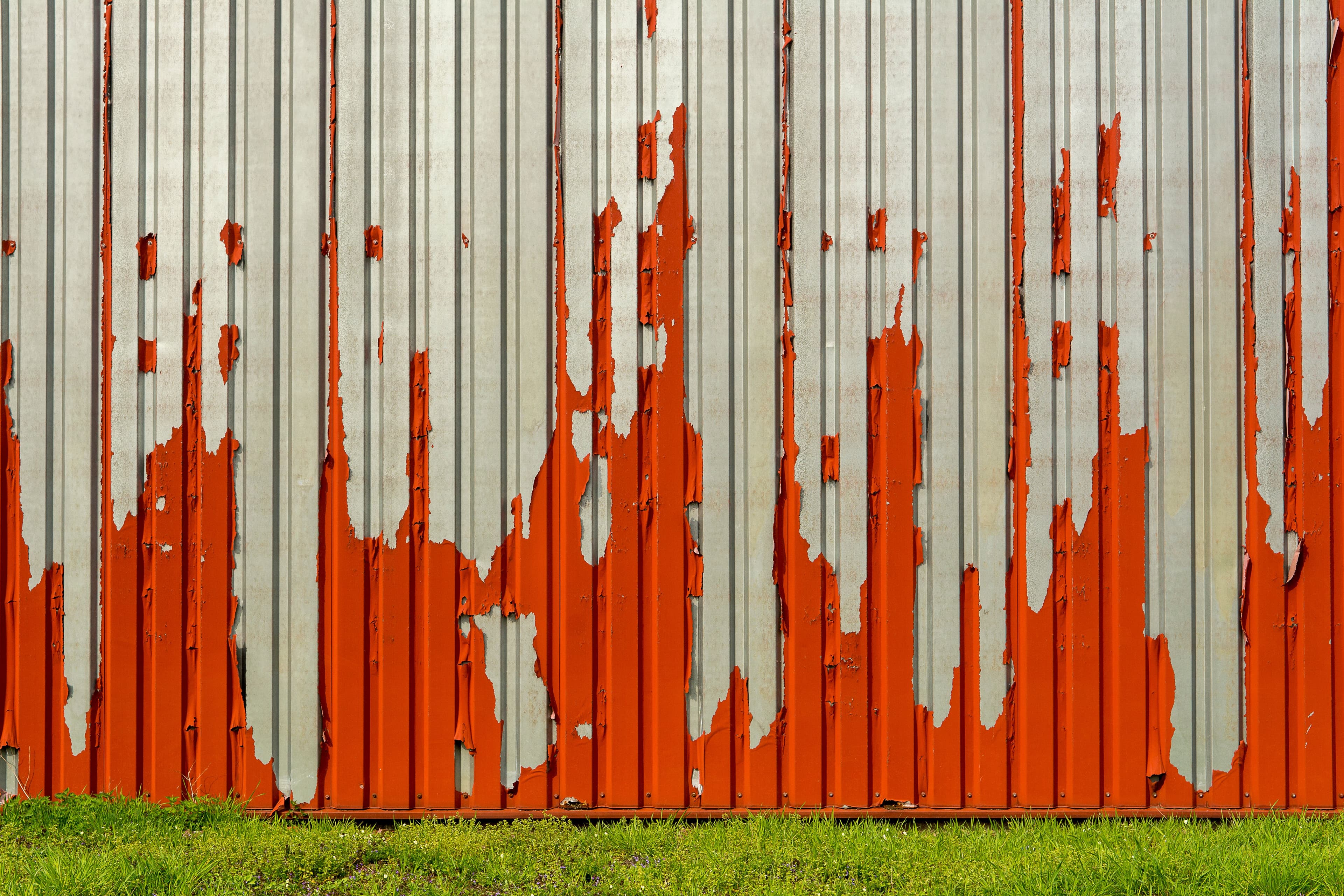 Weathered galvanized corrugated steel wall showing coating wear