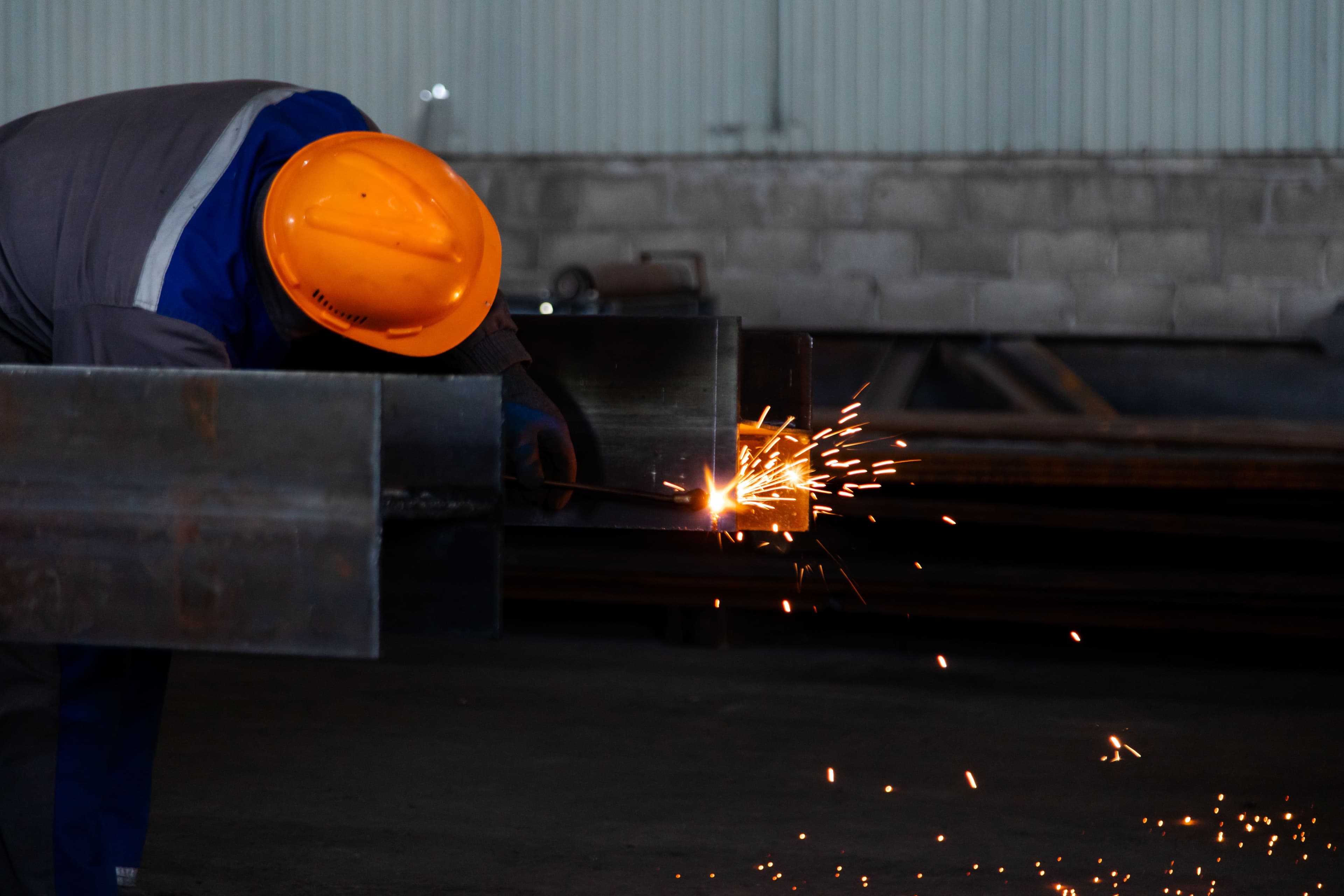 Worker welding a steel beam with sparks, representing quality craftsmanship