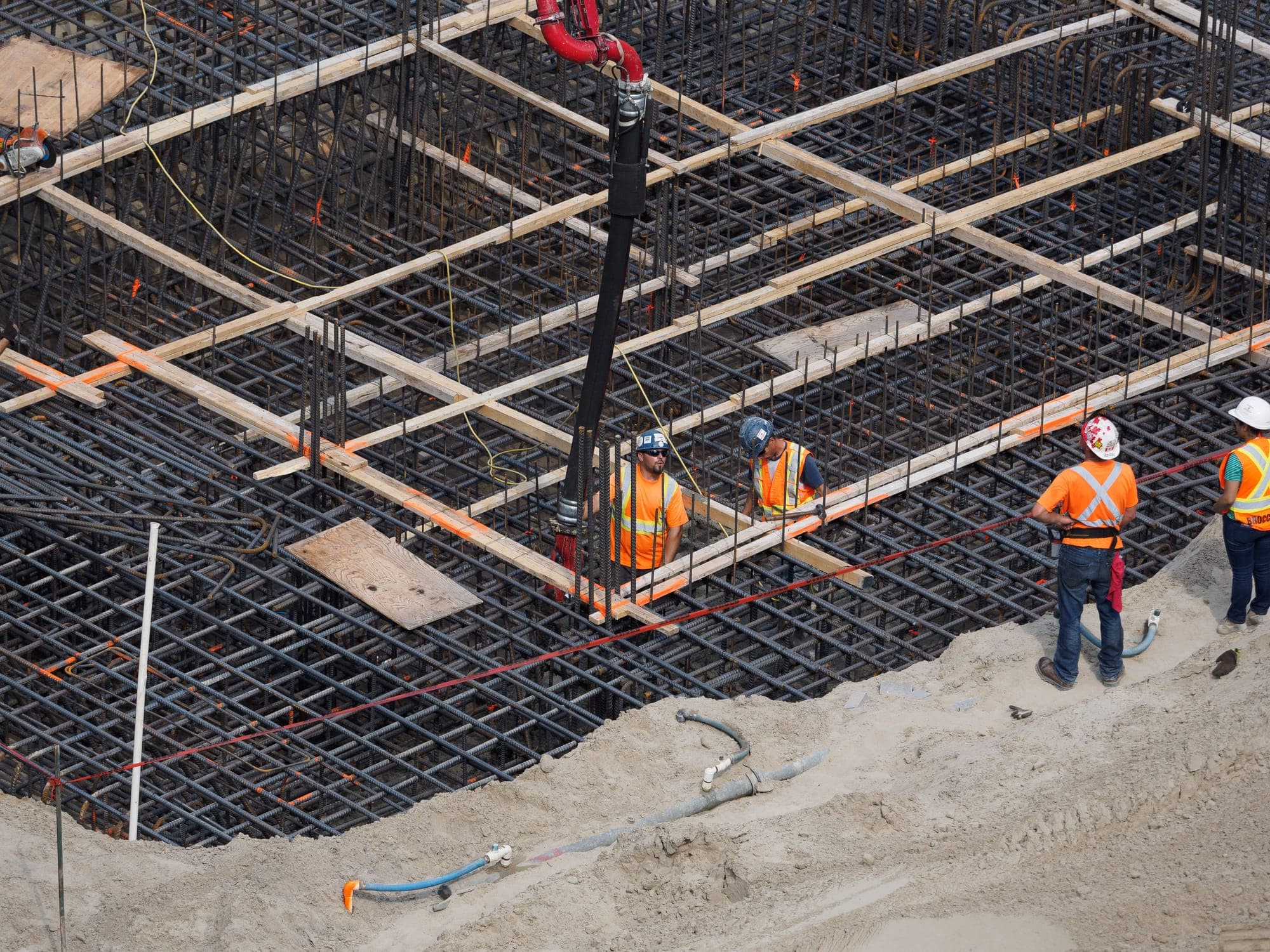 Construction workers reinforcing a steel foundation at a building site