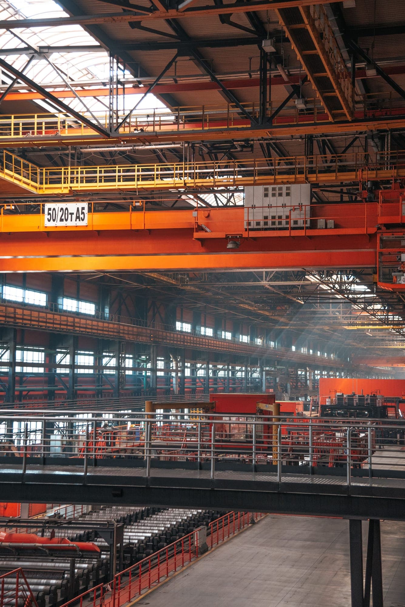 Spacious industrial factory interior with overhead cranes and metal walkways
